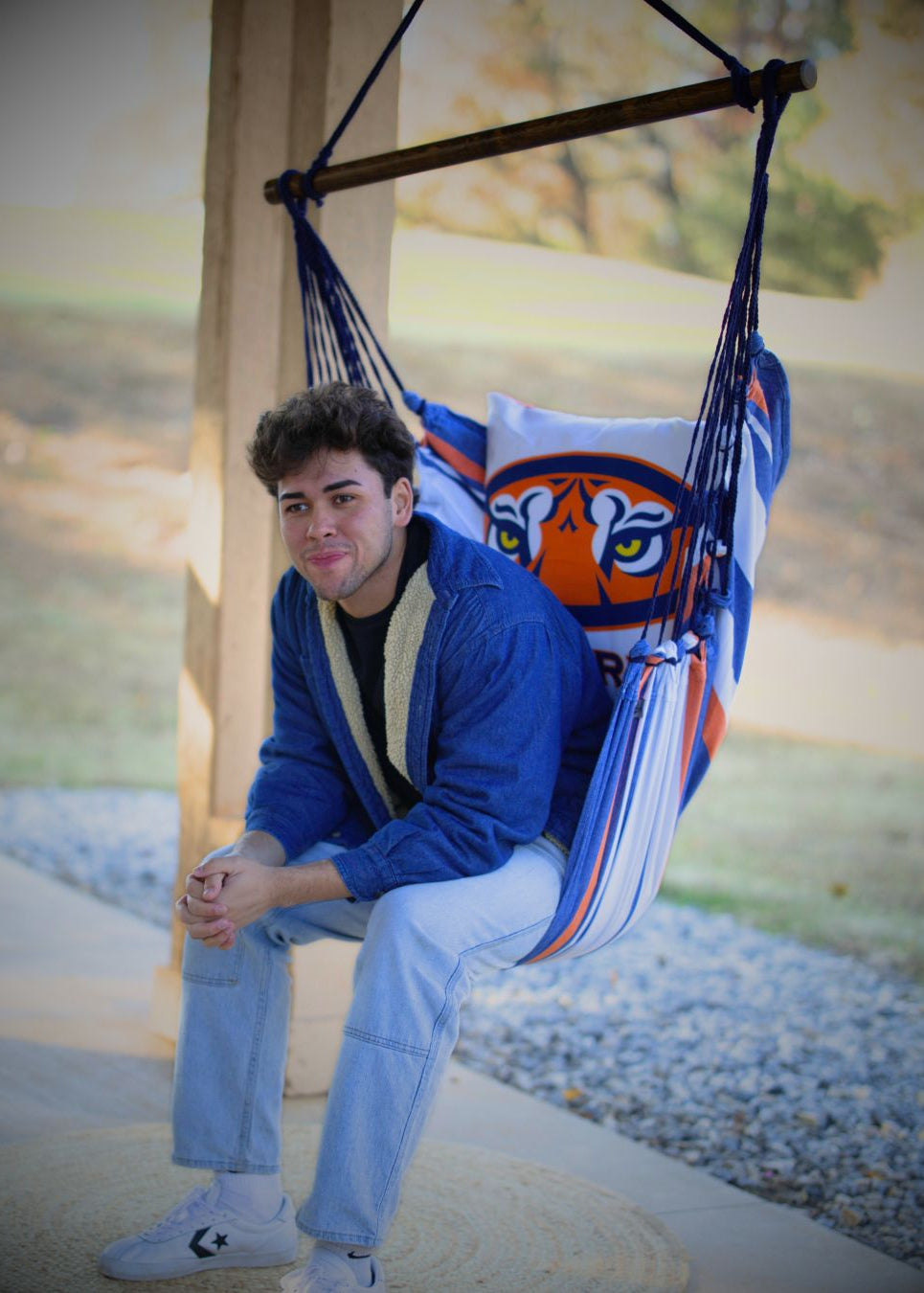 Man sitting in a hammock chair with an Auburn Tiger design in an outdoor setting