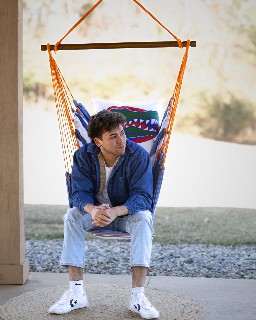 Person sitting in a colorful Florida Gator logo hammock chair outdoors
