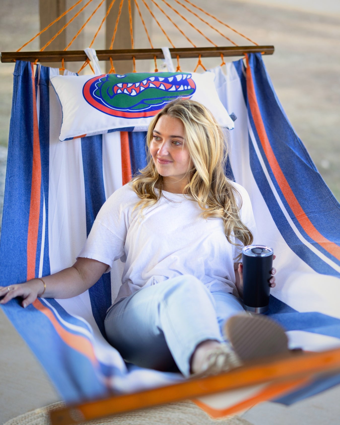 Woman sitting in a hammock with Florida Gators-themed pillows and blanket.