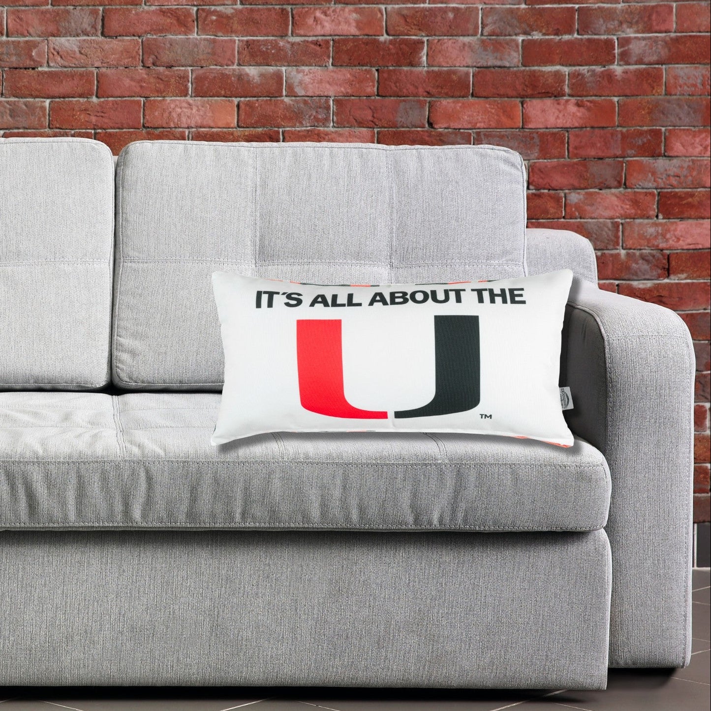 Gray sofa with a University of Miami decorative pillows featuring a U and it says It's All About The U.