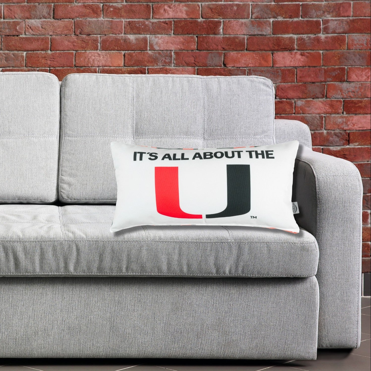 Gray sofa with a University of Miami decorative pillows featuring a U and it says It's All About The U.