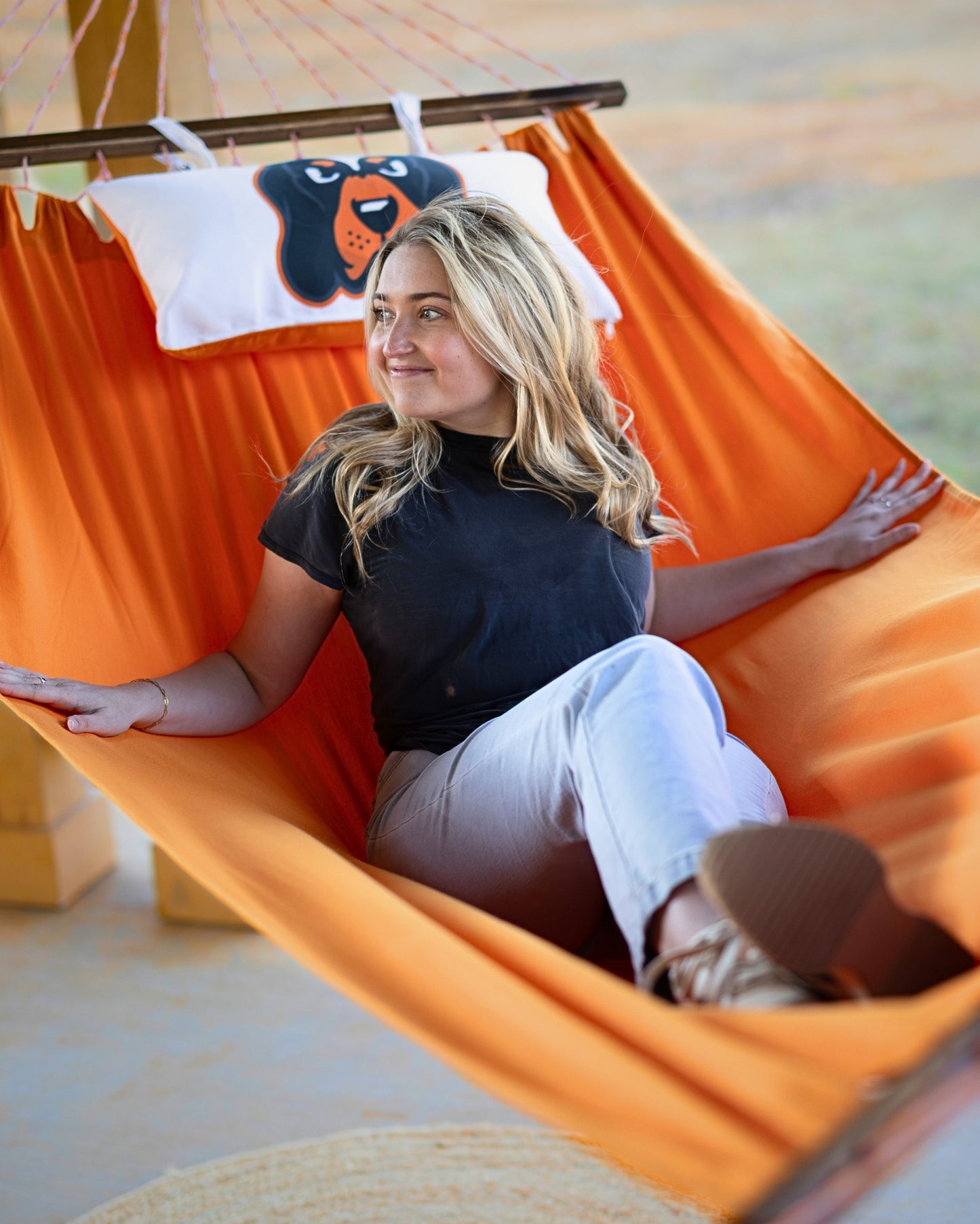 Woman sitting in an orange University of Tennessee hammock outdoors porch