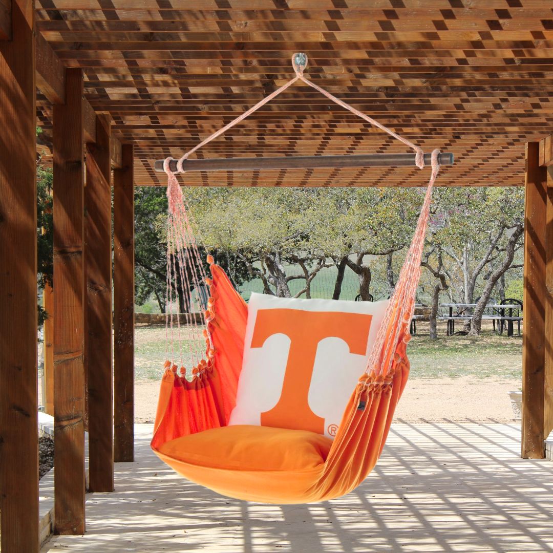 Orange hammock chair with a Tennessee Volunteers logo hanging from a wooden pergola.