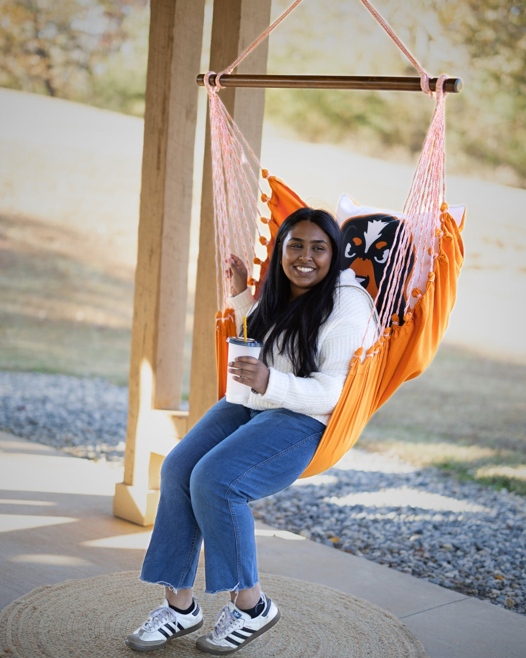 Woman sitting in a UTK Tennessee Smokey hammock chair outdoors decor