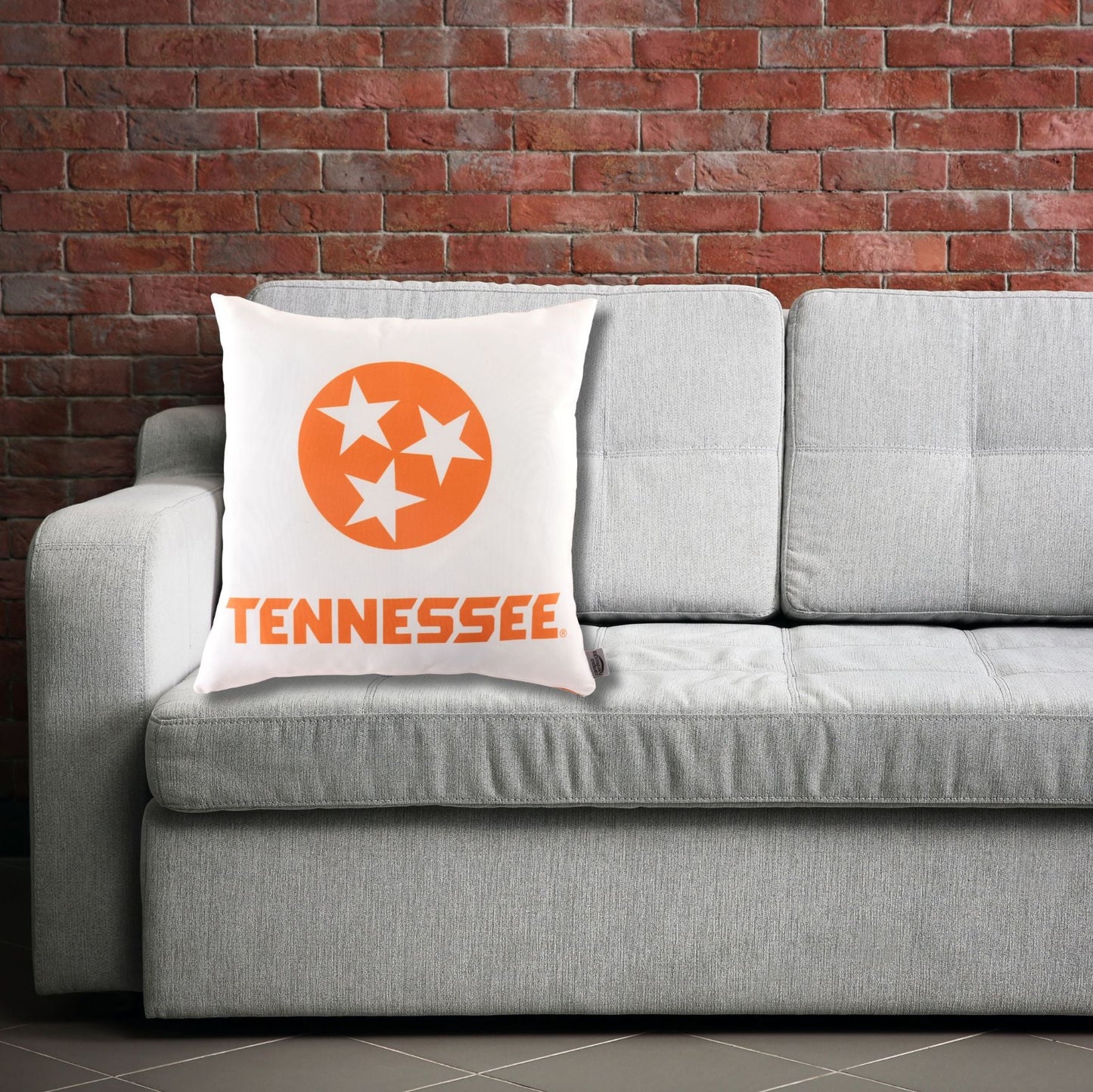 University of Tennessee Pillow on a sofa. Orange and white pillow with Tennessee tri star logo. 