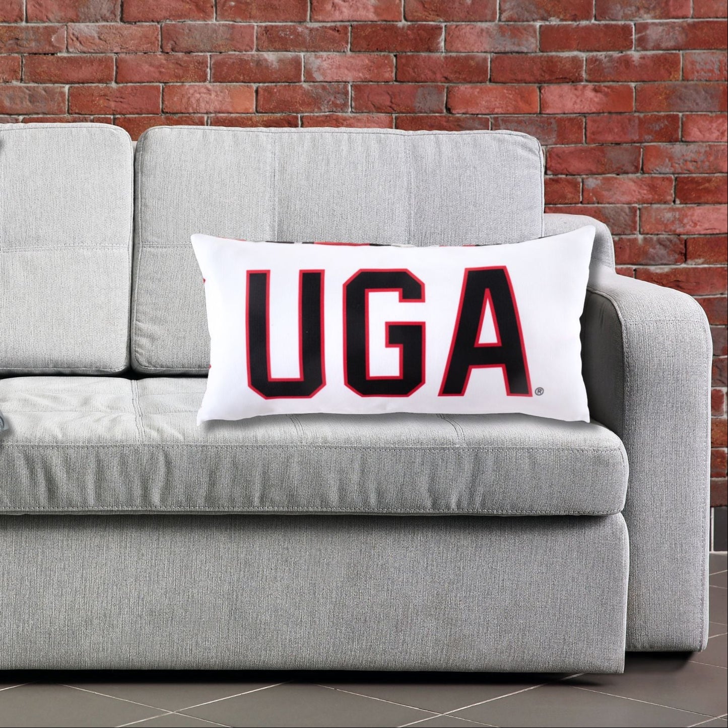 Gray sofa with a decorative pillow featuring the UGA text against for the Georgia Bulldogs