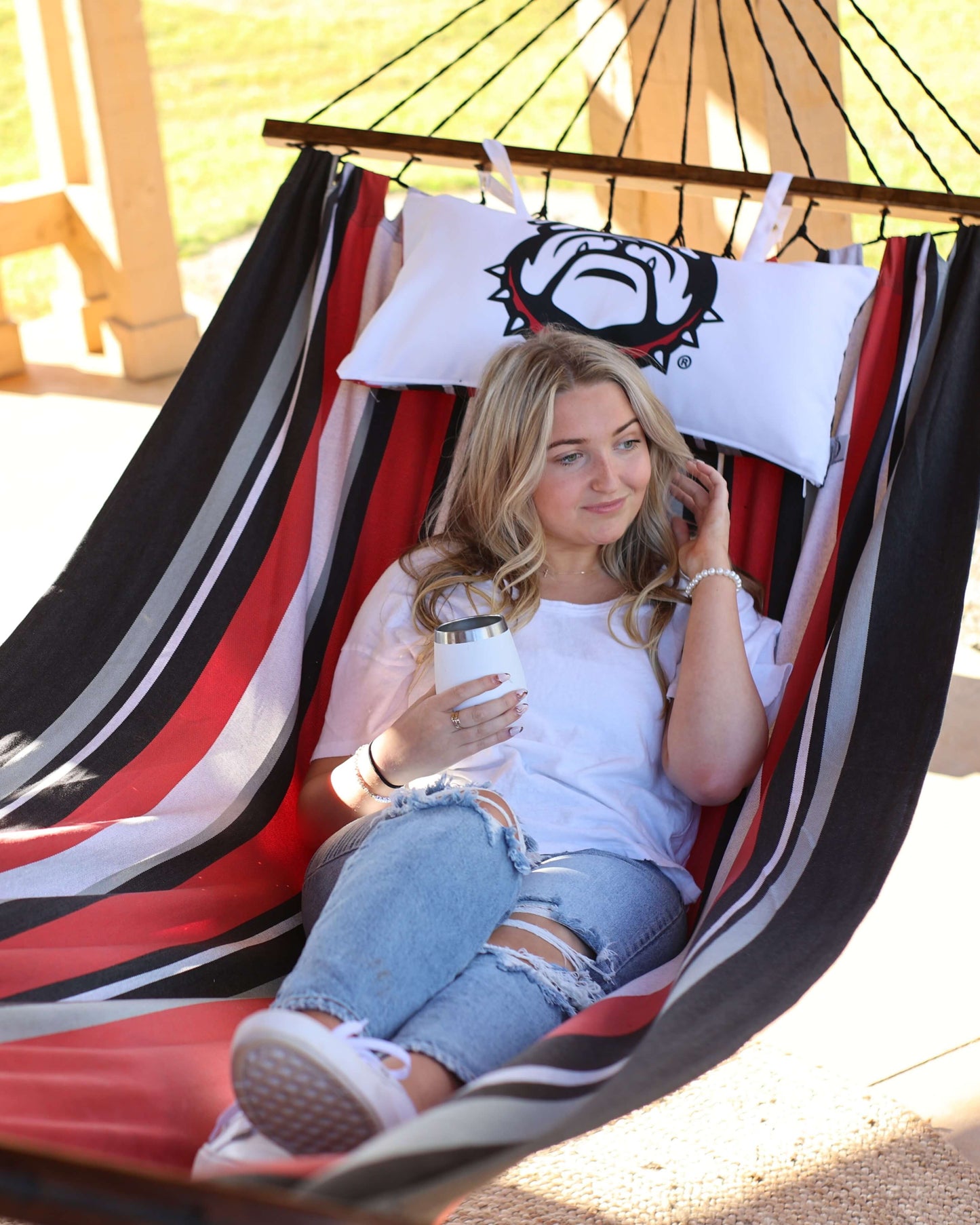 Woman sitting on a Georgia Bulldogs hammock furniture. UGA Gift For Her