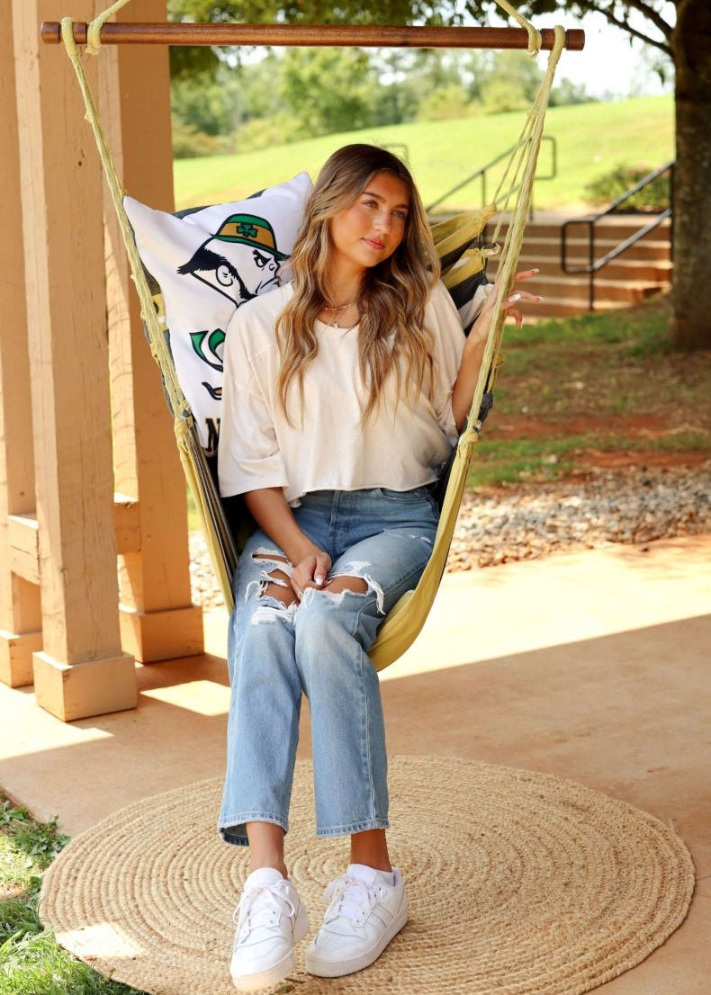 Woman sitting in a Notre Dame Leprechaun hammock chair on a covered patio